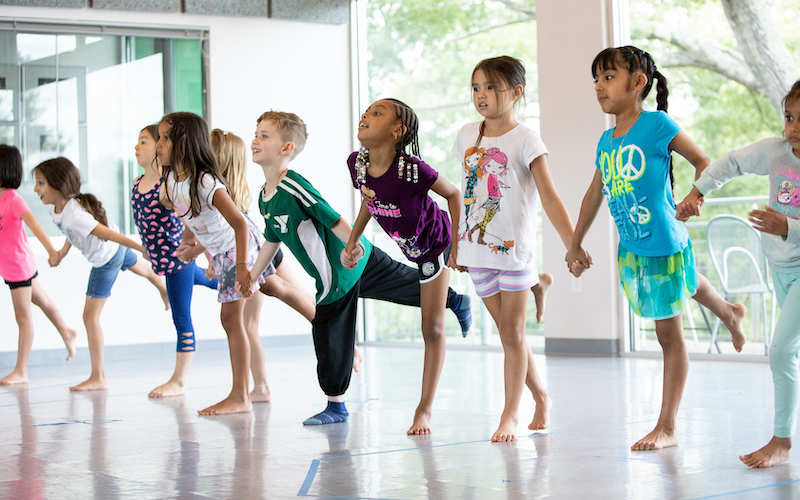 Kids at camp holding hands and standing on one foot