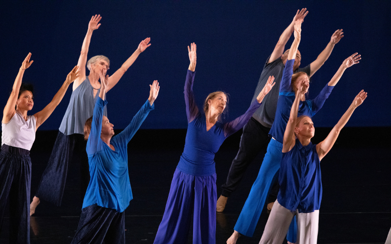 ADF Faculty wearing blue and reaching into the air together