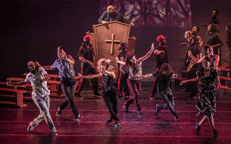 Dancers performing on a stage that is set to look like a church space
