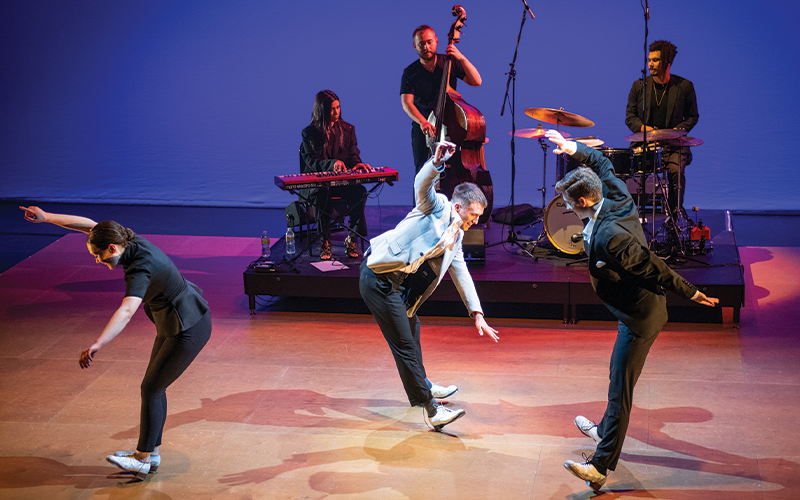 3 dancers tapping onstage while 3 musicians play live behind them